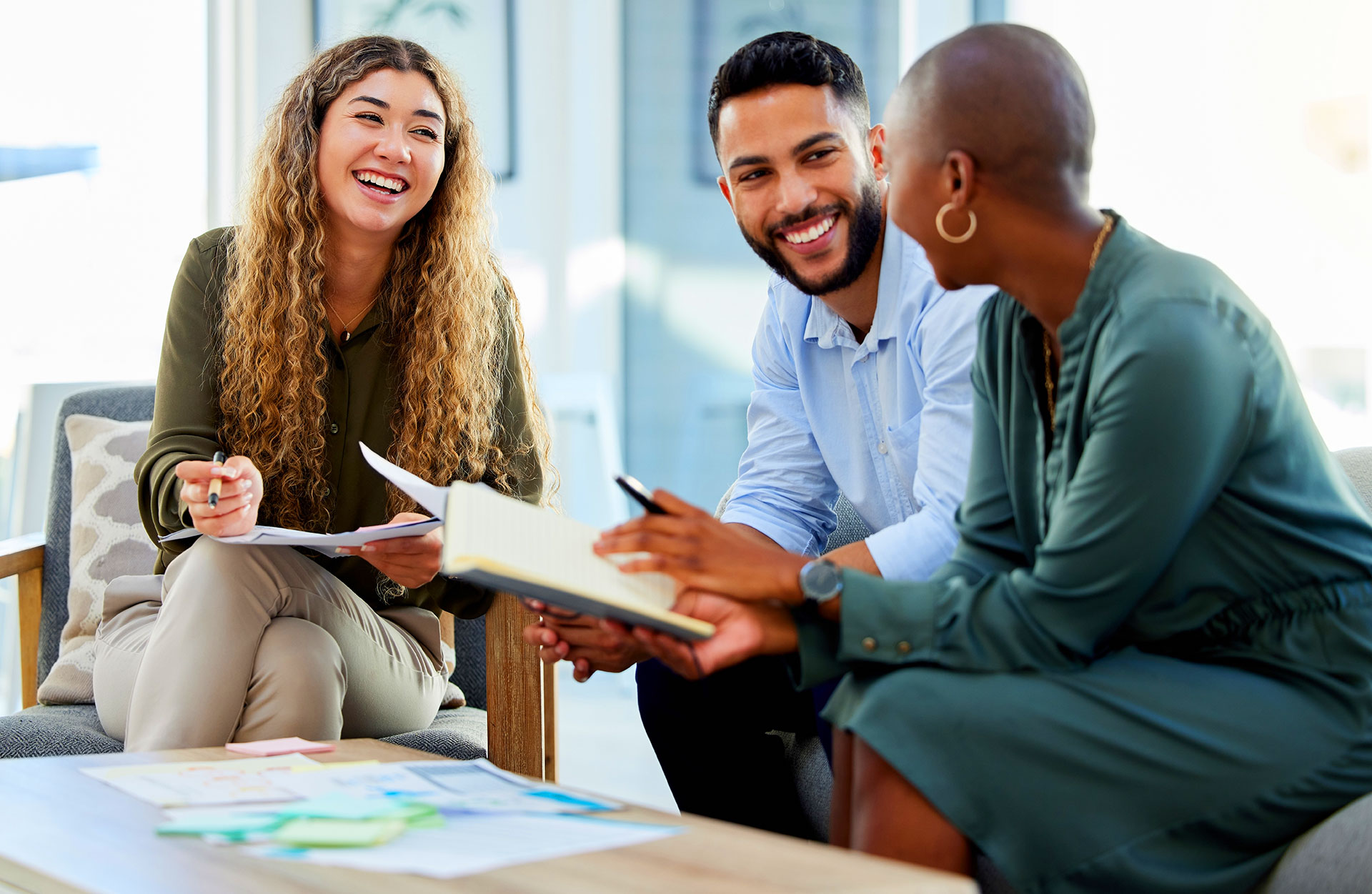 Three colleagues laughing during collaborative team meeting session
